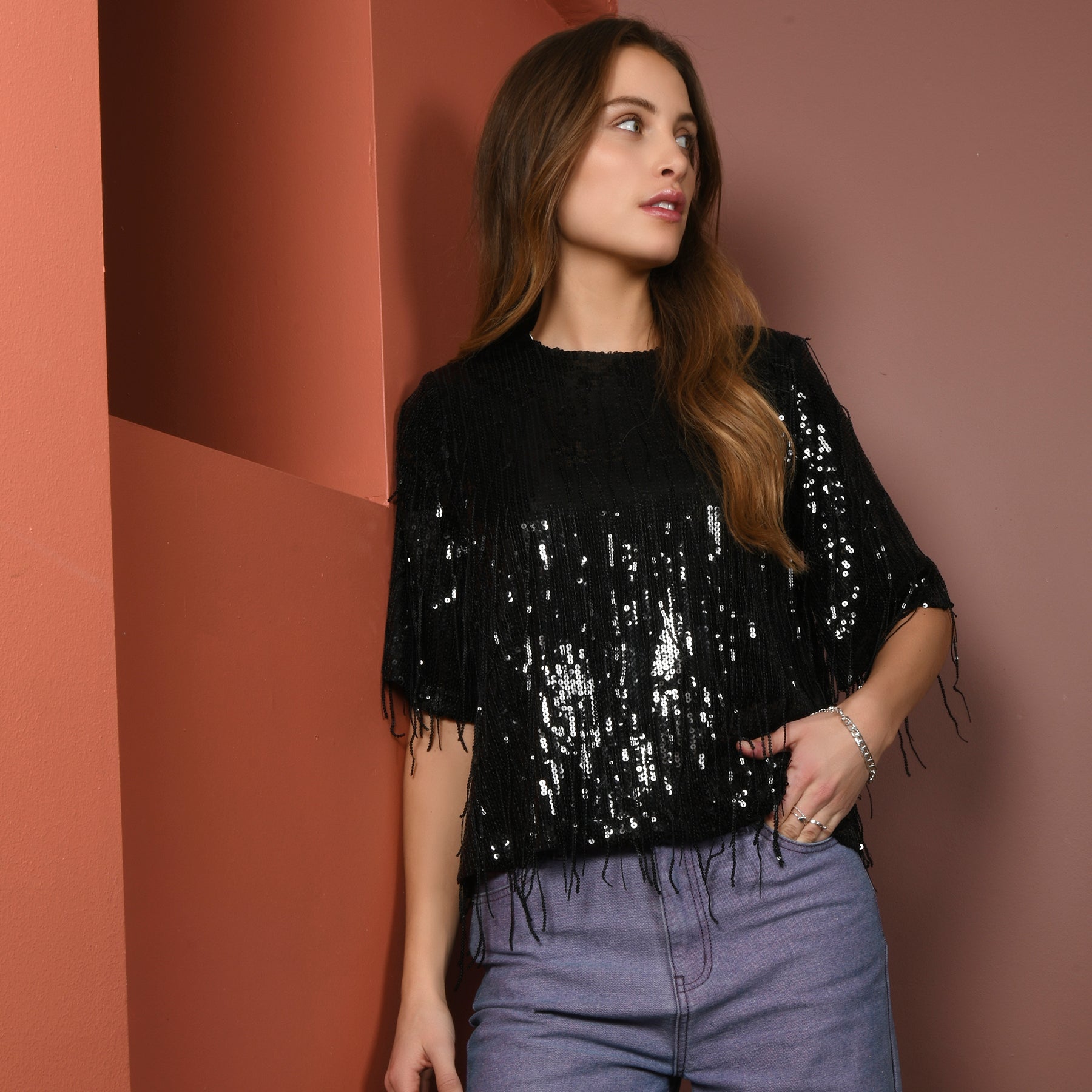 Eine Frau in einem glänzenden schwarzen Top mit Jeans.